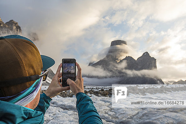 Ein Mann macht mit seinem Smartphone ein Foto vom Berg Asgard.