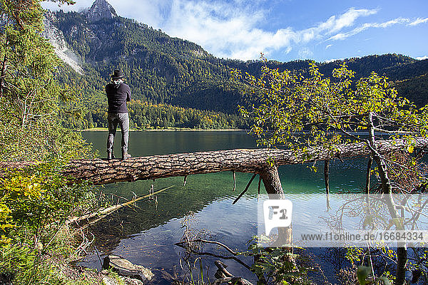 Eine Person blickt an einem sonnigen Tag in Deutschland auf einen klaren Alpensee