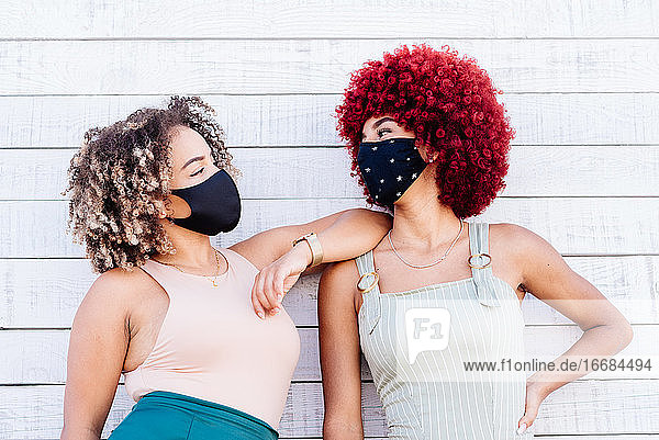 Two latin women with mask in a carefree attitude on a white background