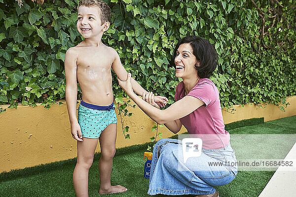 Eine Mutter cremt ihren Sohn mit Sonnencreme ein.