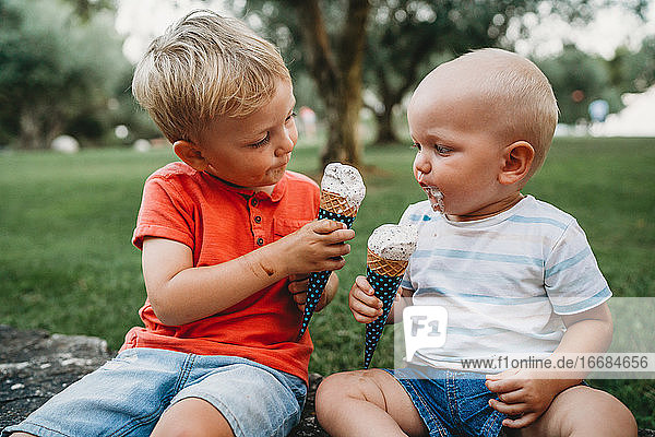 Baby und Kleinkind teilen sich ein Eis und schauen sich an