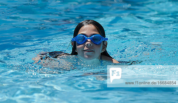 Happy lächelnd Mädchen Schwimmen und Spaß haben im Pool mit blauem Wasser