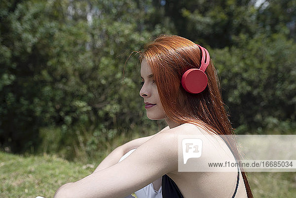 cute red hair girl listening music in the park