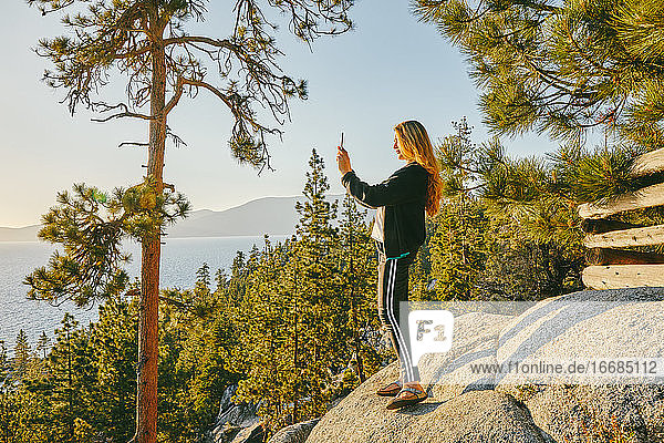 Junge Frau beim Fotografieren des Sonnenuntergangs über dem Lake Tahoe.