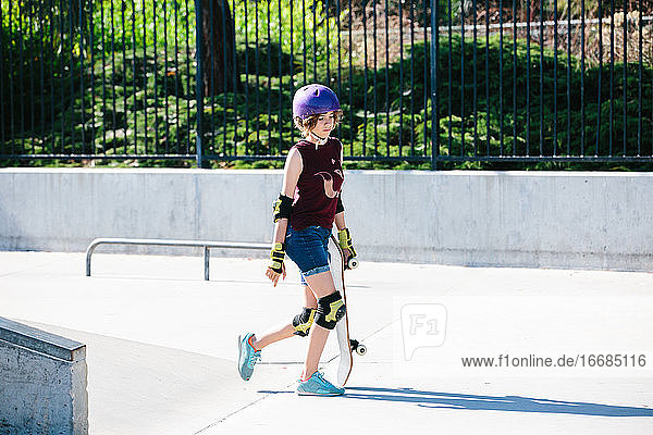 Skaterin geht mit ihrem Skateboard im Skatepark spazieren
