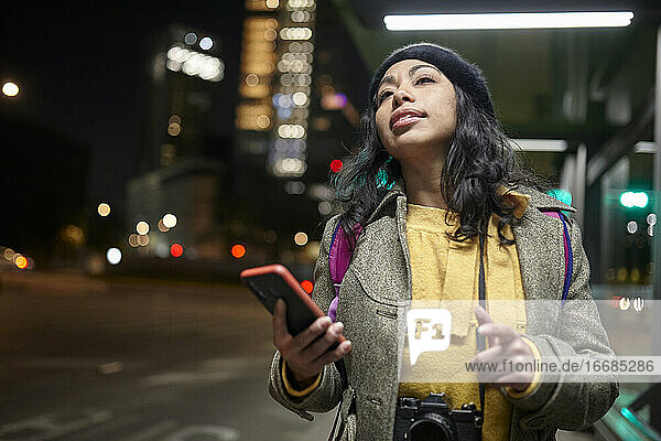 Frau  die nachts auf der Straße auf ihren Uber-Service wartet