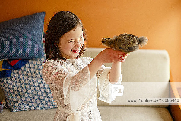 Ein fröhliches Kind hält ein Vogelbaby nahe an sein Gesicht  um es zu untersuchen