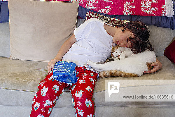 Ein Junge mit verletzter Hand hält einen Eisbeutel und kuschelt mit einer Katze  um sie zu trösten