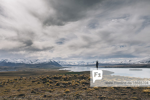 Junge Frau steht in Richtung der Südalpen im Hintergrund Neuseelands