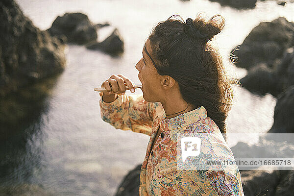 Porträt einer schönen Frau  die sich die Zähne mit einer Bambuszahnbürste putzt