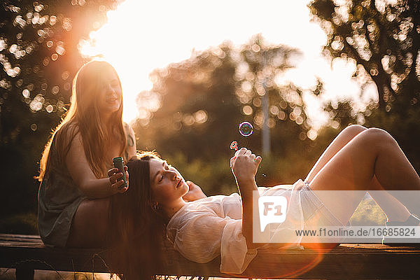 Lesbian couple playing with bubbles while relaxing in park in summer