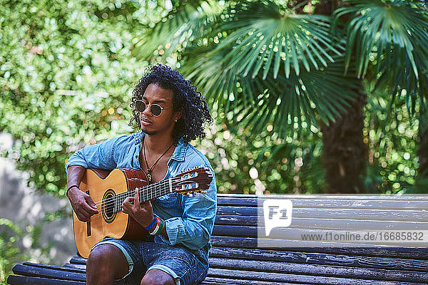Ein Musiker spielt Gitarre in einem schönen Park.