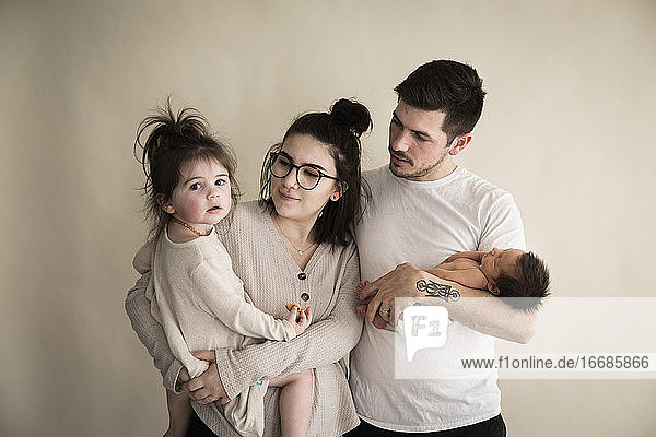 Millenial Hipster Family With Newborn and Toddler With Cream Backdrop