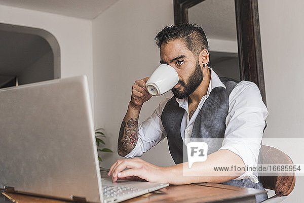 Gutaussehender Mann  gekleidet als Manager  trinkt Kaffee und arbeitet