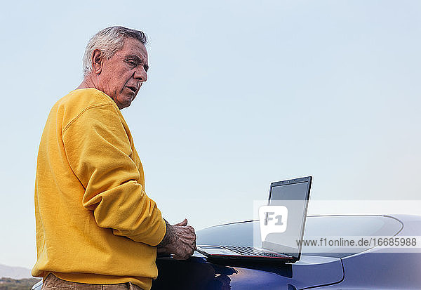 Älterer Mann benutzt Laptop im Auto