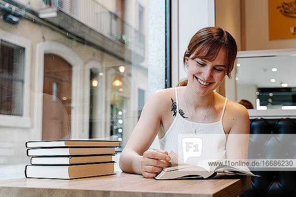 Junge Frau liest Bücher in einem Café