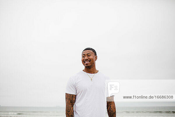 Gemischtrassiger Mann lächelt am Strand