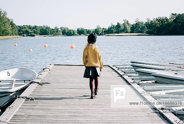 junges Mädchen  das entlang eines Piers in Richtung Meer in Schweden geht
