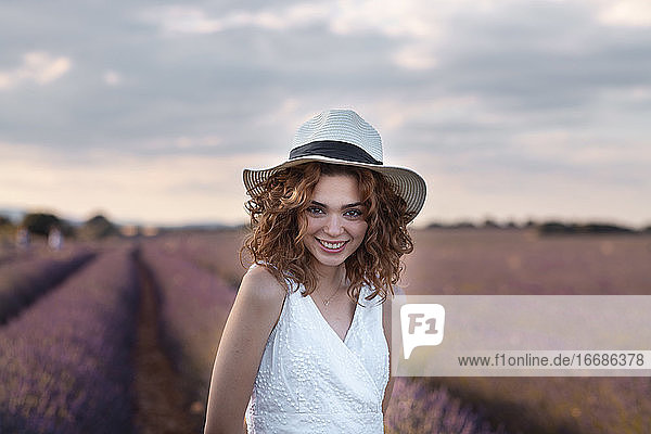 woman with curly hair wearing a hat in a lavender field