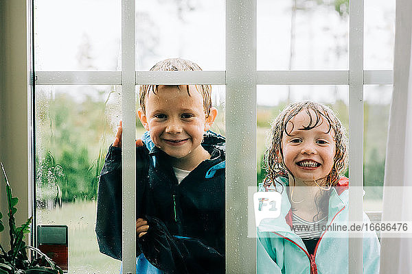 brother and sister stood looking through a window whilst playing