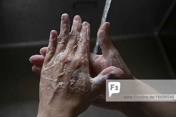 Nahaufnahme von jemandem  der sich die Hände mit Seife im Waschbecken schrubbt