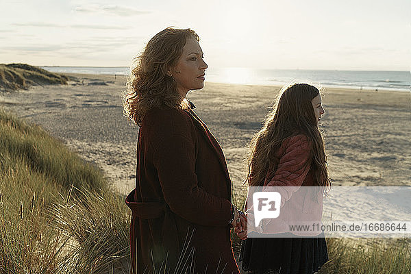 Mother and daughter standing on the beach against seascape view
