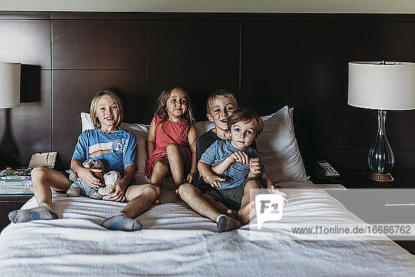 Geschwister sitzen und lächelnd auf dem Hotelbett im Urlaub in Palm Springs