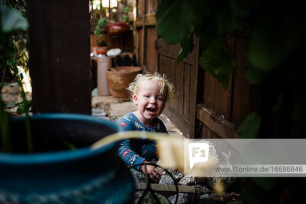 Blond Zweijährige lächelnd & lachend auf der vorderen Terrasse
