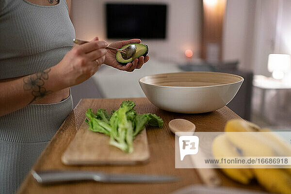 Abgeschnittene Frau bei der Zubereitung eines gesunden Gerichts mit Avocado