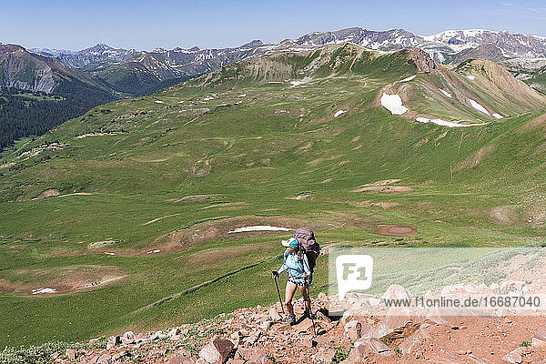 Rückansicht einer Frau beim Wandern auf einem Berg im Sommerurlaub