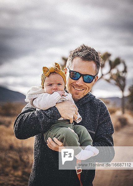 Ein Mann mit einem Baby steht in der Wüste von Kalifornien