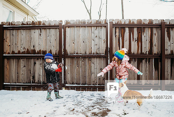Junge Schwester wirft Schneeball auf Bruder im Hinterhof im Winter