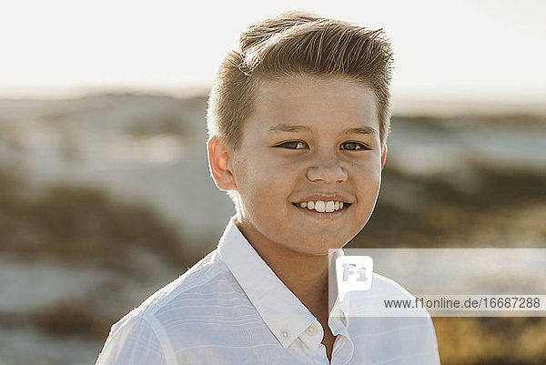 Lächelnder  gepflegter Junge in weißem Hemd mit Knopfleiste