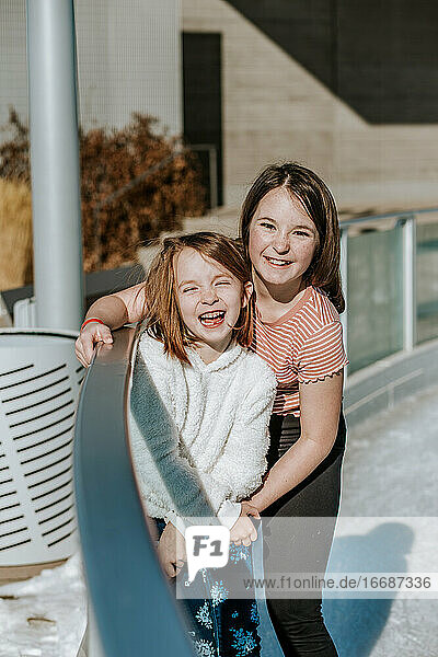 Happy young girls hugging on the side of ice skating rink