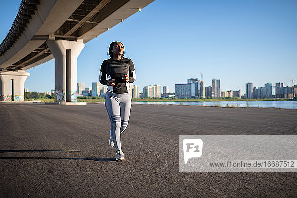 Ethnische Sportlerin läuft unter einer Brücke