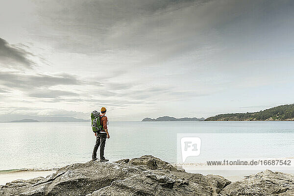 Mann erkundet die Küste und springt über die Felsen