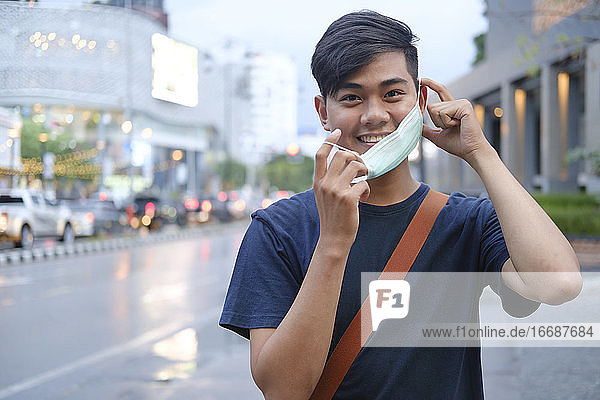 Young man removing mask from face.