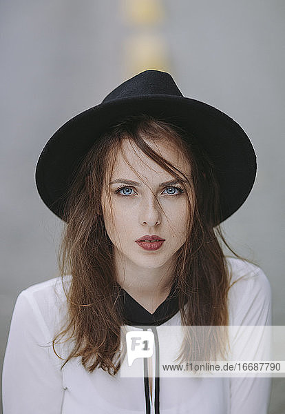 Porträt einer blauäugigen jungen Frau mit schwarzem Hut