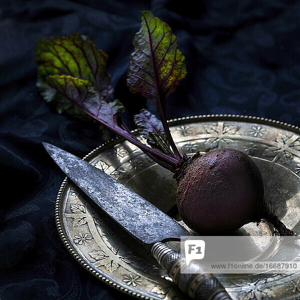 beet with foliage on vintage plate with kitchen knife