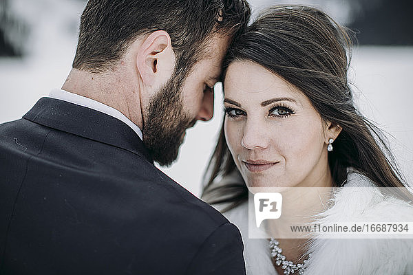 Braut und Bräutigam berühren sich nach der Eheschließung im Winter auf dem Eis an der Stirn