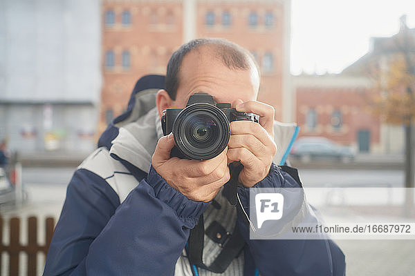 A man takes a picture in front of a mirror on the street in winter