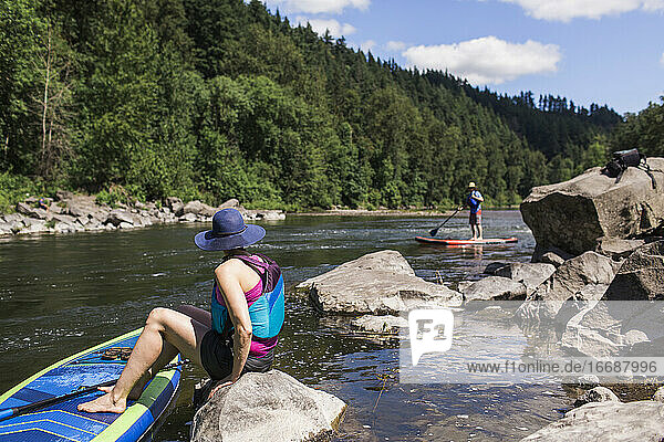 Ein junges Paar genießt den Fluss auf ihren SUPs in Oregon.