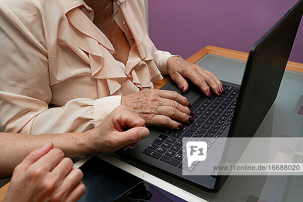 Nahaufnahme einer älteren Frau  die auf einem Laptop tippt