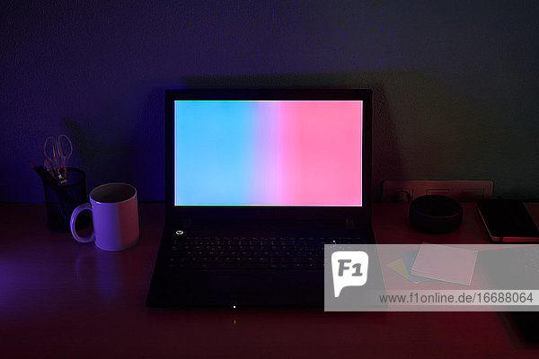 Mit farbigen Lichtern beleuchteter Schreibtisch. Konzept der neuen Technologien