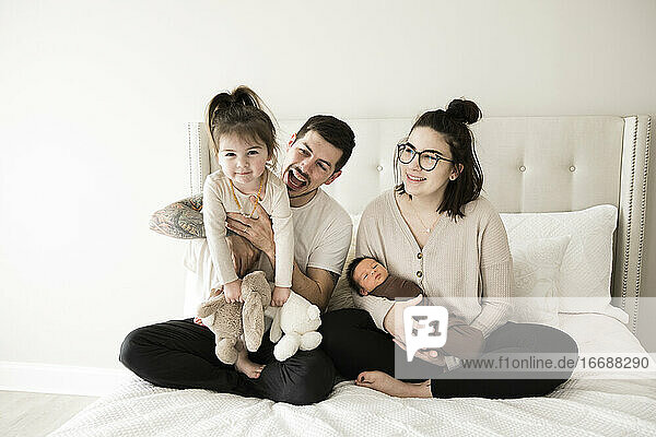 Modern Millennial Family With Toddler and Newborn Plays on White Bed
