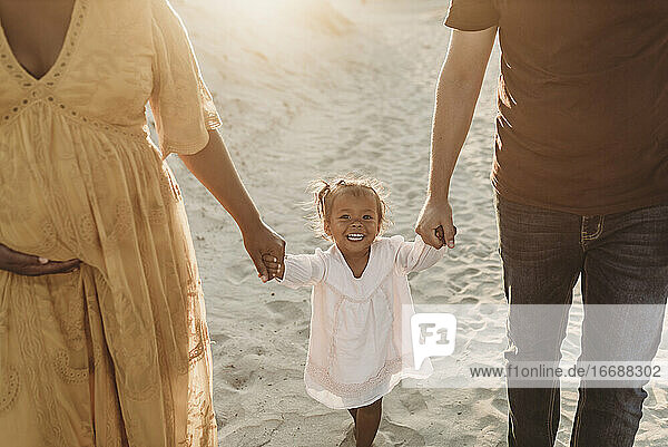 Junge dreiköpfige Familie beim Spazierengehen und Spielen am Strand