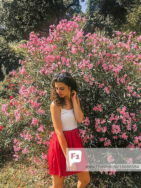 Mädchen im roten Kleid  umgeben von rosa Blumen