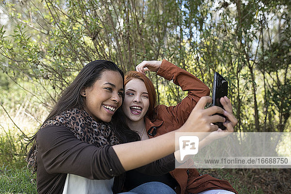 zwei gemischtrassige Frauen machen ein Selfie im Park