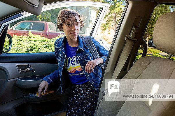 Teenager-Mädchen mit kurzen Haaren steigt mit ihrem Rucksack ins Auto