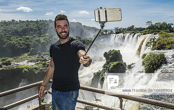 Mann macht ein Selfie mit Einbeinstativ an den Iguazu-Wasserfällen in Argentinien